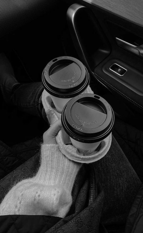 Eine Hand hält zwei Coffee-To-Go Becher in schwarz-weiß